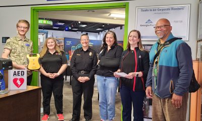 Eugene Science Center staff and others stand in the center's building to receive the donation of an automatic external defibrillator.